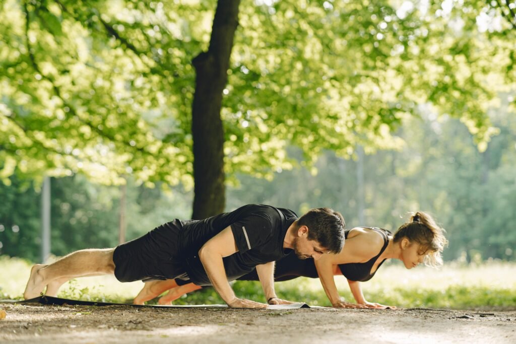 Fit couple doing push-ups in a sunny park, embracing outdoor fitness and healthy living.